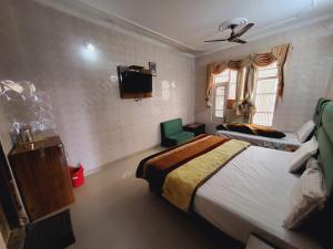 a bedroom with a bed and a couch and a tv at Pratap Resort in Katra +7 photos