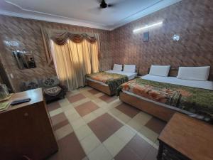 a hotel room with two beds and a table at Pratap Resort in Katra