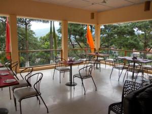 Hāflong的住宿－Landmark Hotels,Haflong，餐厅设有桌椅和大窗户。