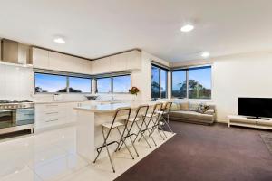 a kitchen with a island with chairs and a couch at Serenity Guest House in Dromana