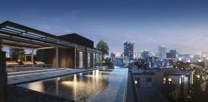 a building with a swimming pool on top of a city at Muay Thai Apartment - Ratchada in Bangkok
