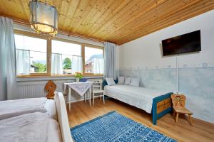 a bedroom with two beds and a table and a tv at Gästehaus Eder Oberammergau in Oberammergau
