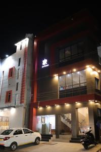 a white car parked in front of a building at night at RUBY Residency in Palni
