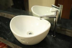 a white sink in a bathroom with a faucet at RUBY Residency in Palni