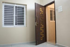 a wooden door in a room with a window at RUBY Residency in Palni