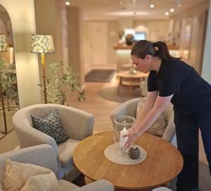 a woman is placing a candle on a table at Hotell Rådhuset in Lidköping