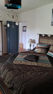a large bed with a black comforter in a bedroom at Aux Volets Bleus in Sibiril