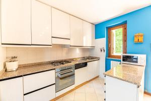 a kitchen with white cabinets and a blue wall at Balcone di Noa e Stella in Menaggio