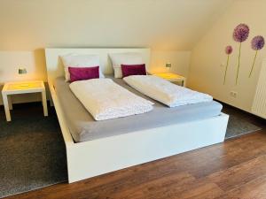 a white bed with two pillows and two tables at Ferienwohnung Villa Südpfalz mit Fernblick in Böchingen
