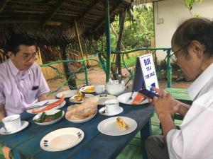 two men sitting at a table with plates of food at Matara Eco Friendly Treehouse in Matara