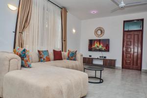 a living room with two couches and a tv at Diani Tulivu in Diani Beach