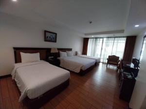 a hotel room with two beds and a chair at Nana Hiso Hotel in Bangkok