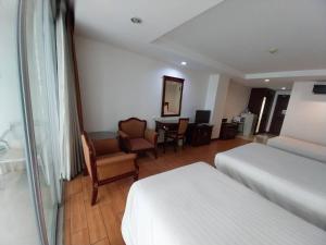 a hotel room with two beds and a desk at Nana Hiso Hotel in Bangkok