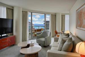 a living room with a couch and a television at Ka Laʻi Waikiki Beach, LXR Hotels & Resorts in Honolulu