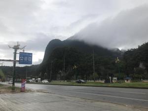 a road with a mountain in the background with a sign at white house in Phangnga