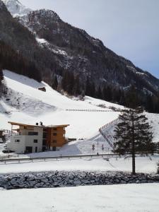 a building on a snow covered slope with a tree at Apart welcom in Ischgl