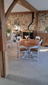a dining room with a wooden table and chairs at Aux Volets Bleus in Sibiril
