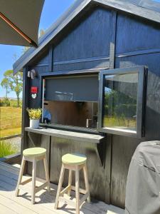 a bar with two stools in front of a building at The Round Tent Raglan in Raglan