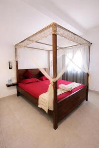 a bedroom with a canopy bed with red sheets at W Hotel Mount Lavinia - Colombo in Colombo +105 photos
