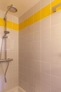 een douche in een badkamer met gele en witte tegels bij Cité Radieuse - Le Corbusier in Marseille