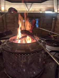 a grill with two sausages cooking over a fire at Home with a view in Storholmen
