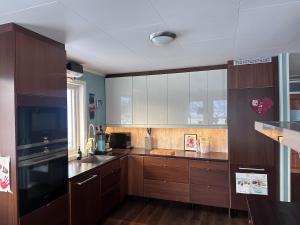 a kitchen with wooden cabinets and a black refrigerator at Home with a view in Storholmen