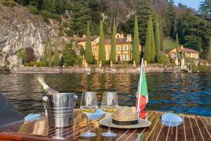 a table with wine glasses and a hat on a boat at Villa Meraviglia - Private Villa with garden, pool and Breathtaking Lake Como Views in Colico