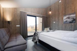 1 dormitorio con cama, sofá y ventana en Arnarstapi Cottages en Stapi