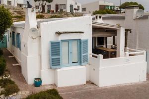 a white building with blue shutters on it at Lekkerlag in Paternoster