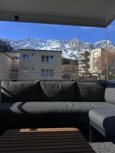 a couch in front of a large window with snow covered mountains at Spacious 2 bedroom apartment in Engelberg