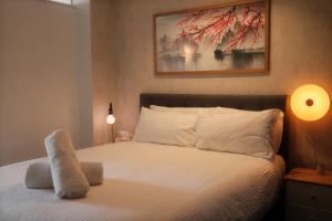 a bedroom with a white bed with a painting on the wall at Chapel Street Hideaway in Melbourne