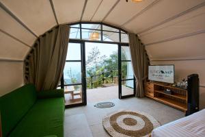 a room with a green couch and a large window at Luxcamp Selo - Merapi View by Horison in Selo +38 photos