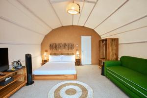 a bedroom with a bed and a green couch at Luxcamp Selo - Merapi View by Horison in Selo