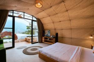 a bedroom with a bed and a large window at Luxcamp Selo - Merapi View by Horison in Selo