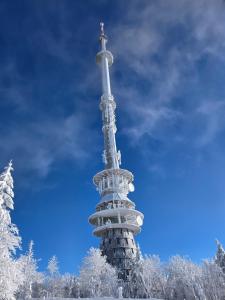 a snow covered tower with a cross on top of it at Ochsenkopf-apartment in Bischofsgrün