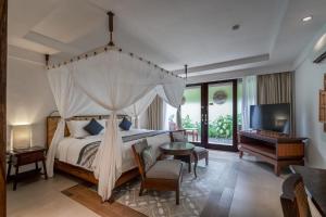 a bedroom with a bed and a tv and a desk at Rama Beach Resort and Villas in Kuta