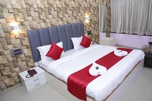 a bedroom with a large bed with red and white pillows at Hotel White House in Navi Mumbai