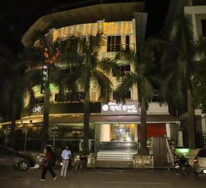 a building with palm trees in front of it at Hotel White House in Navi Mumbai
