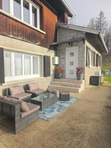 eine Terrasse eines Hauses mit einem Sofa und einem Tisch in der Unterkunft Vertu'Ose avec jacuzzi in Morbier
