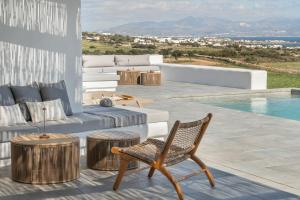 a patio with a couch and a chair next to a pool at Lolantonis - 3BR Sea View & Infinity Pool - Thymari in Aspro Chorio Paros