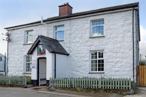 a white brick house with a fence in front of it at Bwch yn Uchaf B&B in Llanuwchllyn