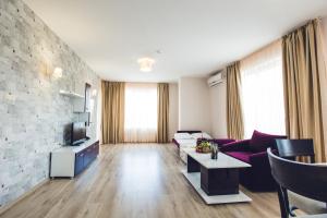 a living room with a couch and a tv at Avenue Deluxe Hotel in Sunny Beach