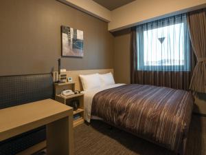 a hotel room with a bed and a window at Hotel Route Inn Grand Kitami Ekimae in Kitami