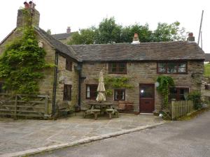 an old stone house with a picnic table in front of it at Colourmill cottage in Leek