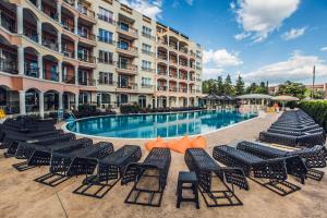 a hotel swimming pool with black chairs in front of a building at Avenue Deluxe Hotel in Sunny Beach