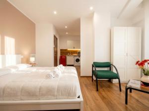 a bedroom with a white bed and a green chair at Bengasi Central Loft in Stazione Bari Centrale