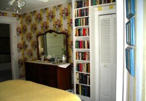 een slaapkamer met een spiegel en een boekenplank met boeken bij Belgravia B&B in Truro