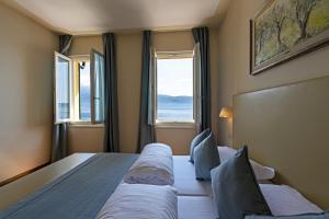 a hotel room with two beds and two windows at Hotel Baia D'Oro - Adults Only in Gargnano