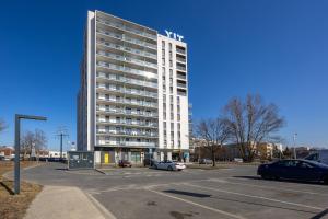 a tall white building with cars parked in a parking lot at Mehoffera Superior Apartment by BookingHost in Warsaw