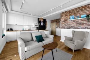 a living room with a couch and two chairs and a kitchen at Mehoffera Superior Apartment by BookingHost in Warsaw